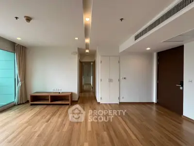 Spacious modern living room with wooden flooring and natural light, ideal for comfortable living.