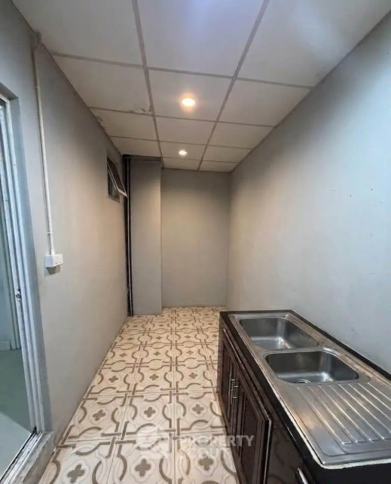 Compact kitchen area with dual sink and patterned tile flooring