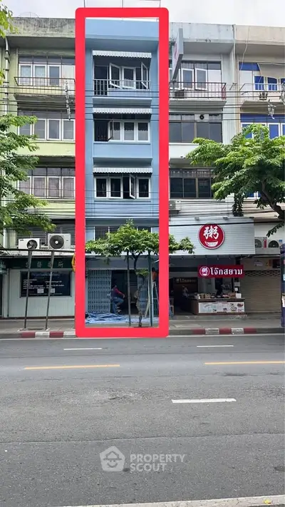 Unique narrow blue building with commercial space on bustling street, ideal for urban living or business.