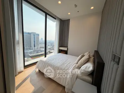Modern bedroom with large window offering stunning city view in high-rise apartment.