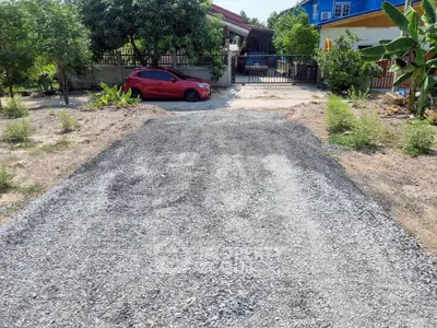 Spacious driveway leading to a charming suburban home with lush greenery and a red car parked.