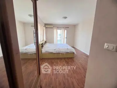 Spacious bedroom with wooden flooring and natural light