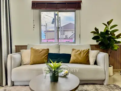 Cozy living room with stylish sofa, large window, and indoor plant, perfect for relaxation and comfort.