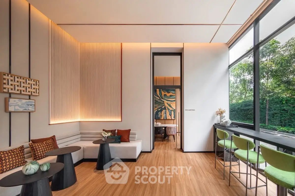 Modern living room with stylish decor and large windows offering lush garden views.