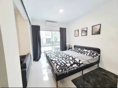 Modern bedroom with stylish decor and large window offering natural light.