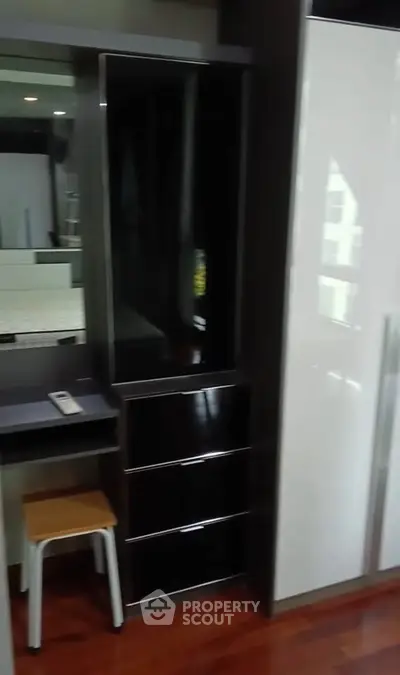 Modern bedroom with sleek black and white wardrobe and wooden flooring