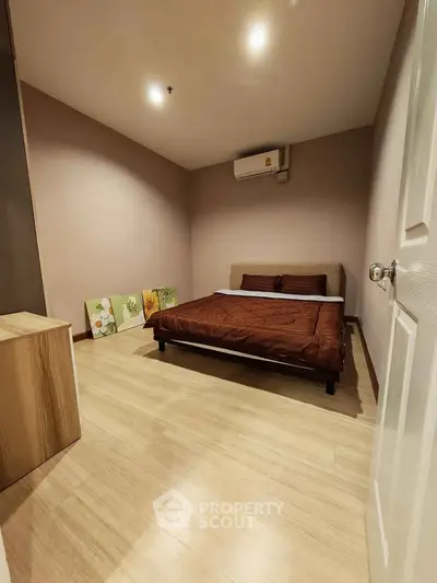 Cozy bedroom with modern decor and wooden flooring, featuring a comfortable bed and ambient lighting.