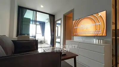 Modern living room with sleek furniture and large TV in a stylish apartment.