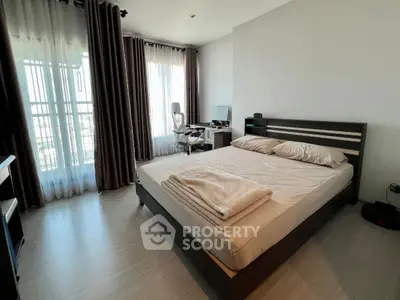 Modern bedroom with large windows and natural light, featuring a sleek bed and workspace.