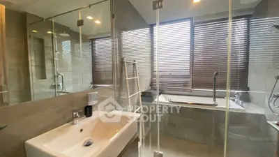 Modern bathroom with glass shower and bathtub, featuring sleek design and natural light.