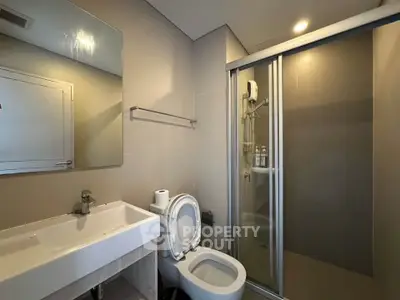 Modern bathroom with sleek fixtures and glass shower enclosure in a contemporary apartment.