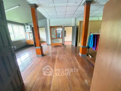 Spacious wooden-floored room with large windows and elegant wooden columns, perfect for versatile living space.
