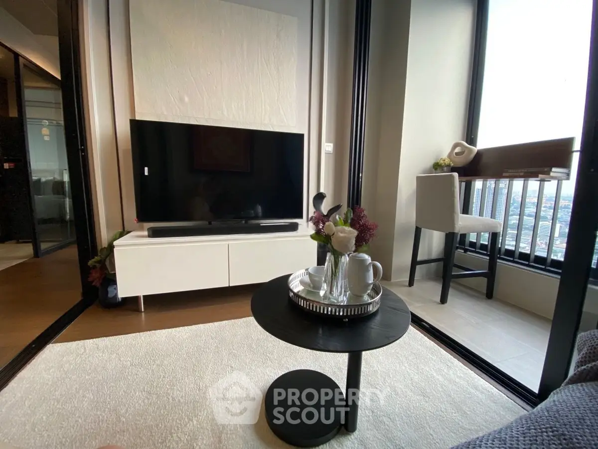 Modern living room with large TV, elegant decor, and city view balcony.