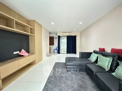 Spacious modern living room with sleek black sofa and built-in wooden shelving, perfect for stylish urban living.