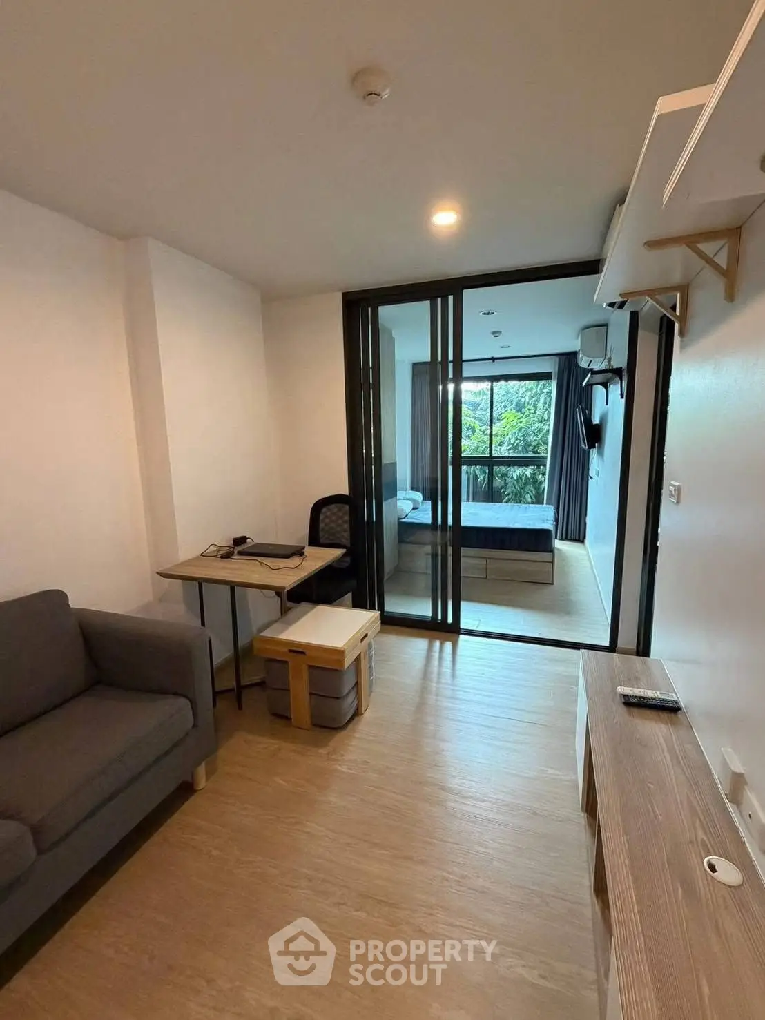 Modern apartment interior with cozy living area and sliding glass doors to bedroom.