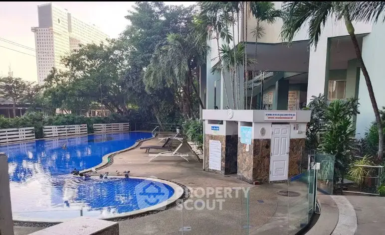 Modern building entrance with lush greenery and sleek architectural design.