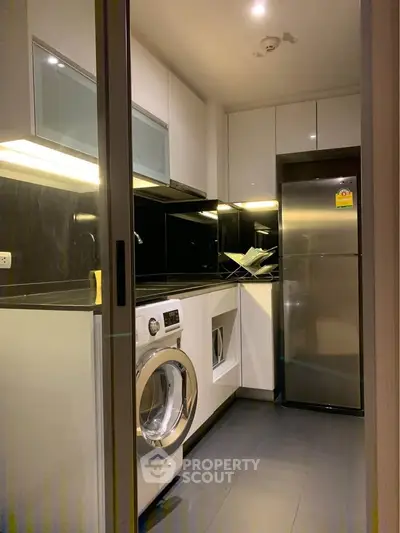 Modern kitchen with sleek appliances and washing machine in compact layout