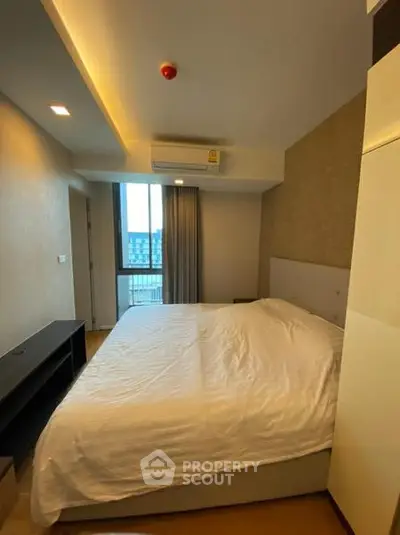 Modern bedroom with large window and air conditioning in a stylish apartment.