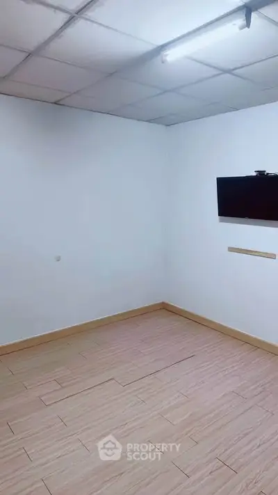 Minimalist room with wooden flooring and wall-mounted TV, ideal for a cozy living space.