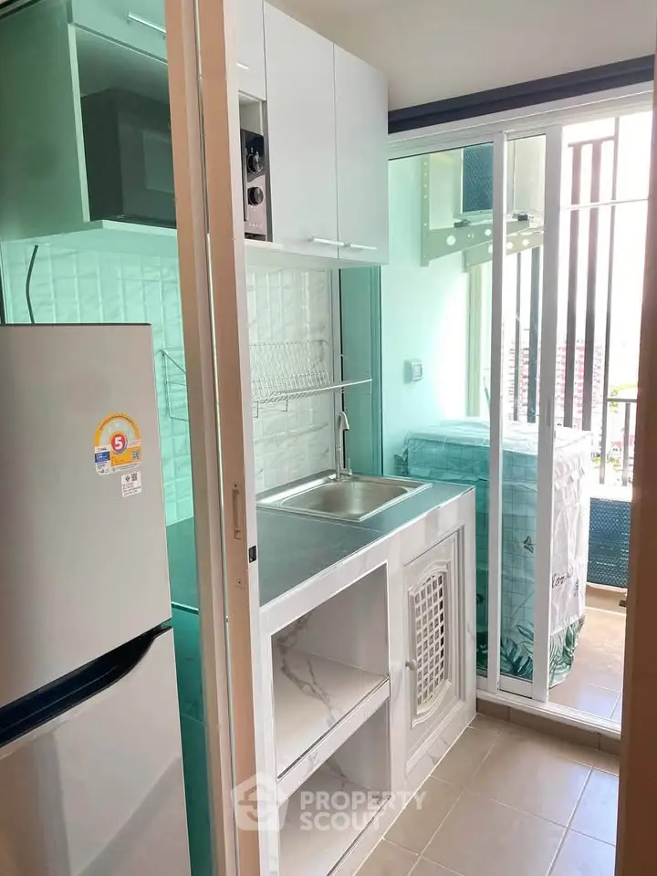 Compact modern kitchen with sliding glass door and balcony view