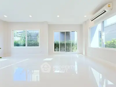 Spacious and bright living room with large windows and modern air conditioning unit.