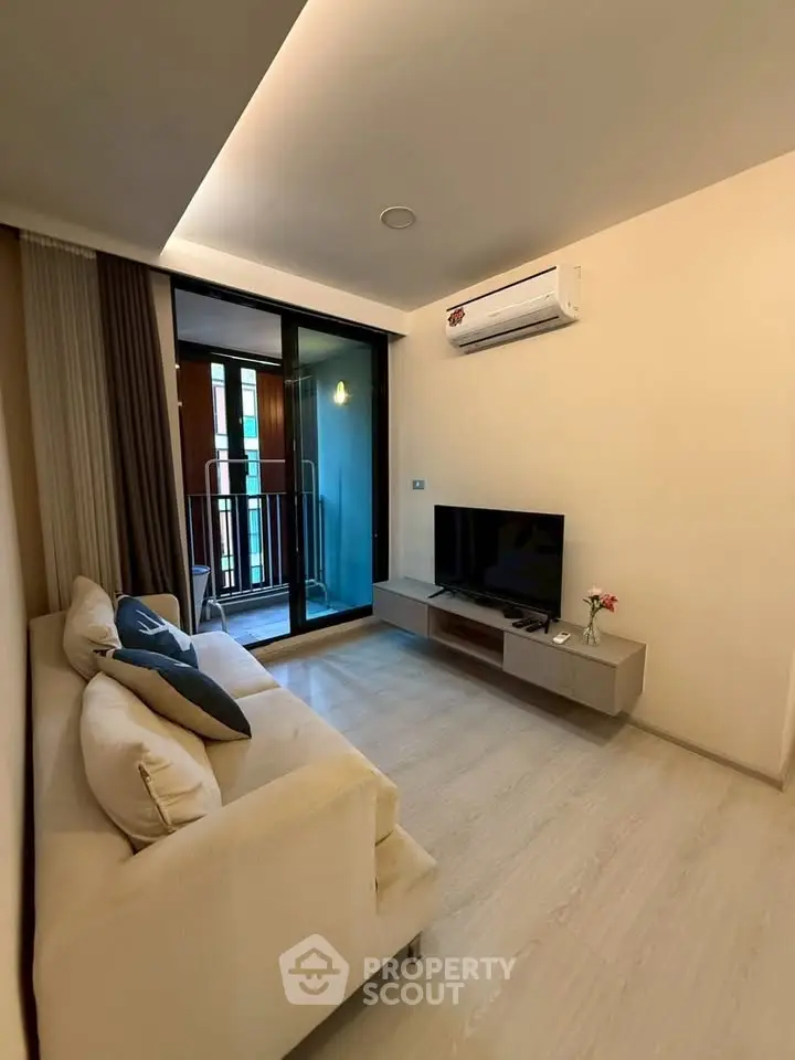 Modern living room with sleek design, featuring a cozy sofa, wall-mounted TV, and balcony access.