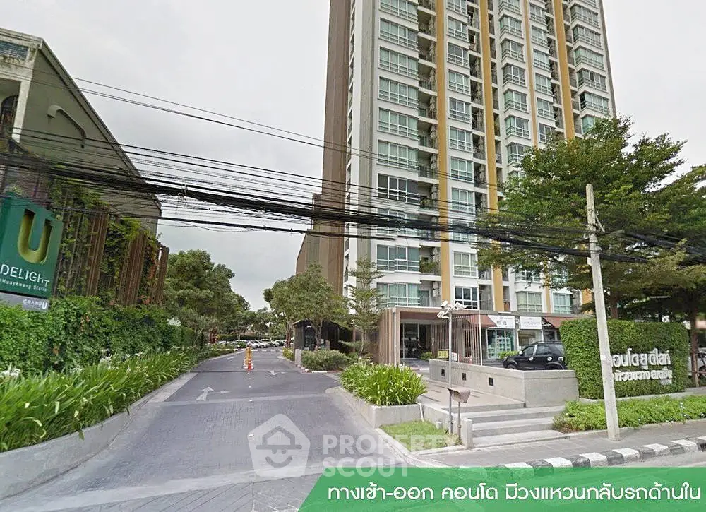 Modern high-rise condominium with lush greenery and secure entrance in urban setting.