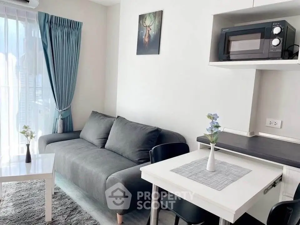 Modern living room with sleek sofa, dining table, and microwave in a bright apartment.