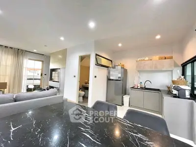 Modern open-plan living room and kitchen with sleek design and marble dining table.