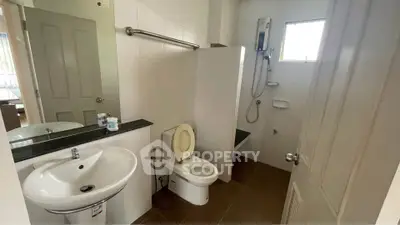 Modern bathroom with sleek fixtures and natural light, featuring a shower and toilet.