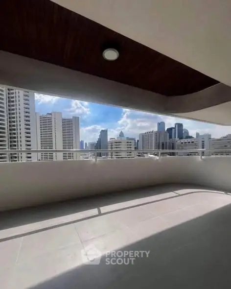 Spacious balcony with stunning city skyline view in modern high-rise apartment.