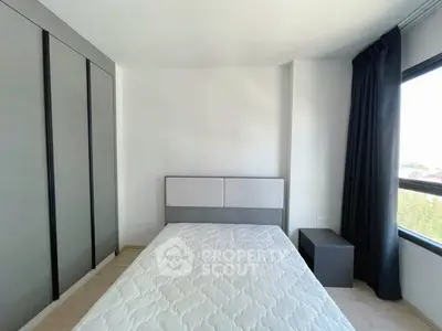 Modern minimalist bedroom with single bed and large window offering natural light.
