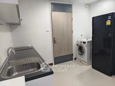 Modern kitchen with sleek black countertop, washing machine, and refrigerator.