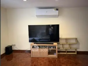 Spacious living room with modern TV setup and wooden flooring