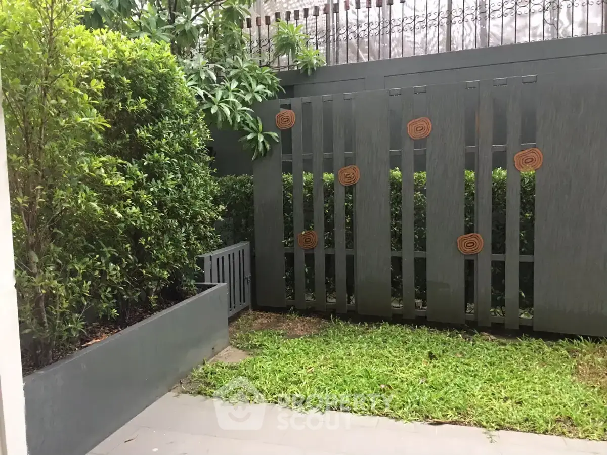 Charming garden area with lush greenery and modern fence design, perfect for relaxation and outdoor enjoyment.
