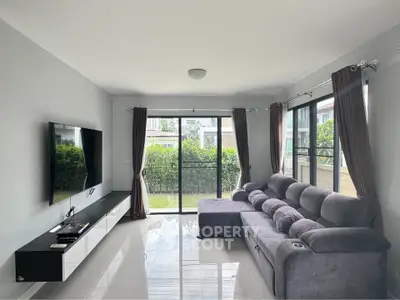Modern living room with sleek furniture and large windows overlooking a garden.