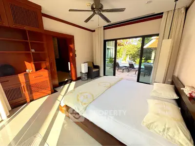 Spacious bedroom with large windows opening to a private balcony, featuring elegant wooden furniture and modern decor.