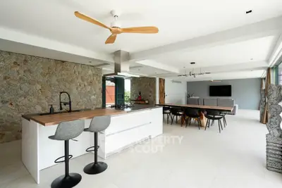Luxurious open-plan kitchen and living area with modern design and stone accent wall.