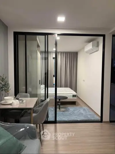 Modern studio apartment with glass partition, cozy dining area, and stylish decor.