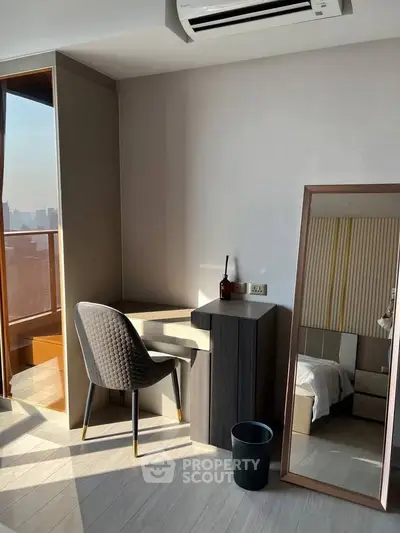 Modern bedroom corner with desk, chair, and full-length mirror, featuring natural light and city view.