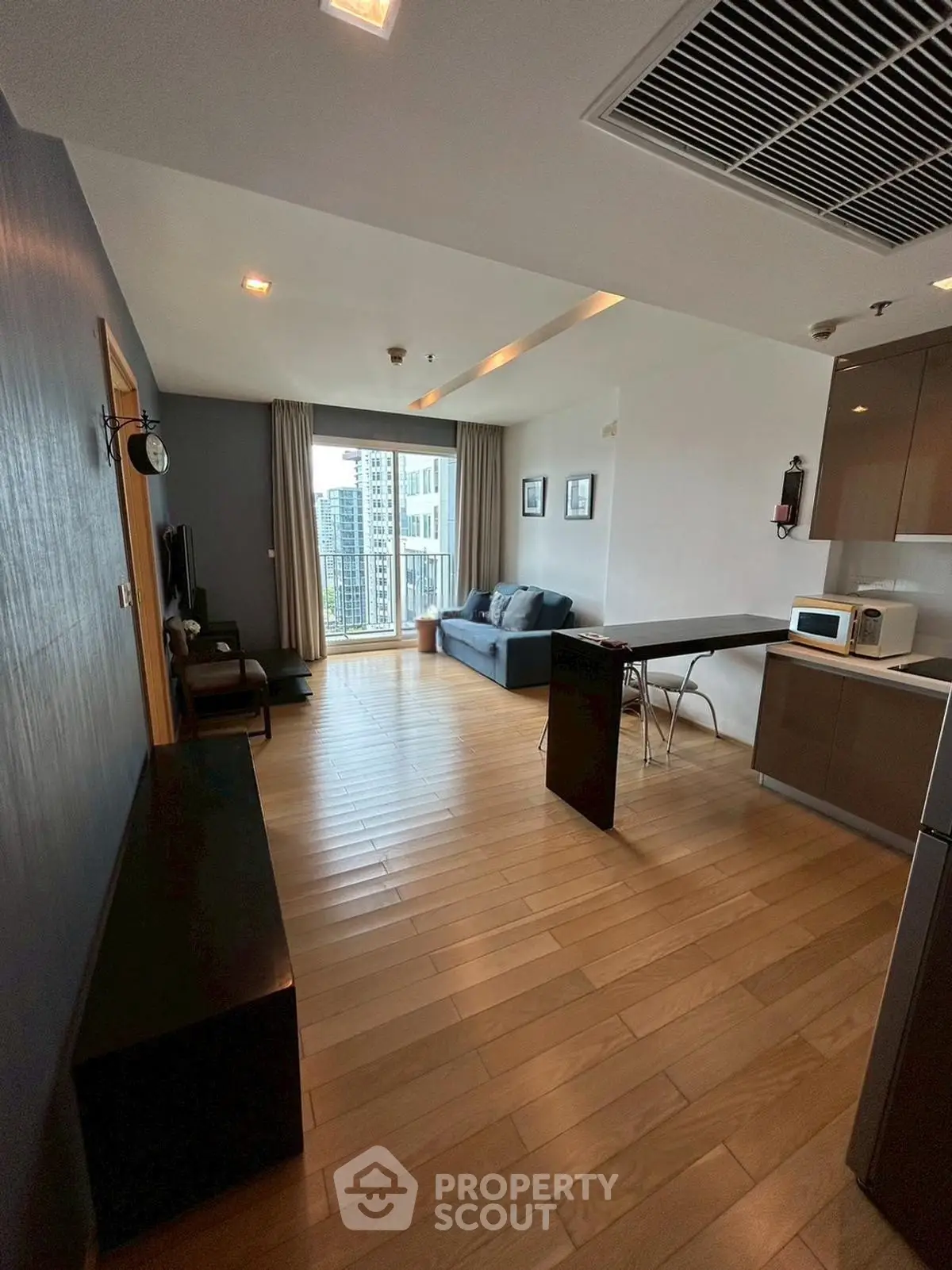 Modern open-plan living room with city view and sleek kitchen area