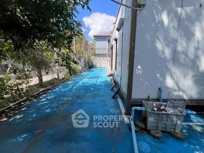 Spacious outdoor area with blue flooring and fenced surroundings, ideal for versatile use.