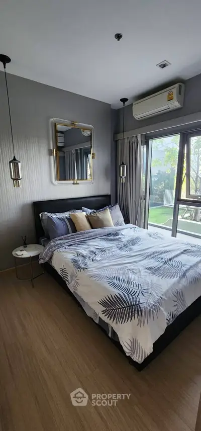 Modern bedroom with stylish decor and large window offering natural light and garden view.