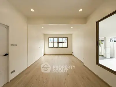Spacious empty room with large windows and wooden flooring, perfect for customization.