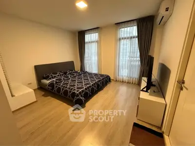 Spacious bedroom with modern decor and large windows in a stylish apartment.