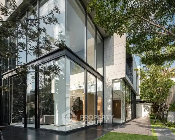 Modern luxury home with floor-to-ceiling windows and lush garden view.