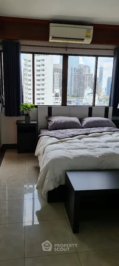 Modern bedroom with city view, featuring large windows and stylish decor in a high-rise apartment.