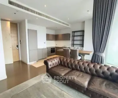 Modern open-plan living room with stylish kitchen and leather sofa in luxury apartment.