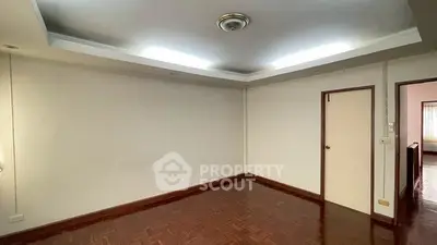 Spacious empty room with wooden flooring and recessed lighting