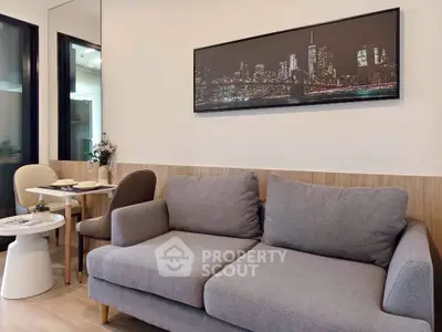 Modern living room with stylish gray sofa and cityscape artwork, adjacent to cozy dining area.